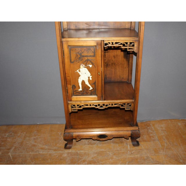 A Japanese-style cherrywood and marquetry cabinet, decorated with flowers and a figure, with a bronze dragon ascending the...