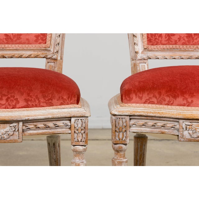 A pair of antique French Louis XVI style side accent chairs sourced from Paris, France. with trapezoidal upholstered backs...