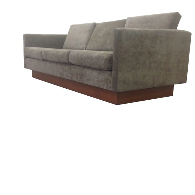 Modern mid century style sofa with walnut base. The sofa is done in a olive green chenille. The frames is made of alder....