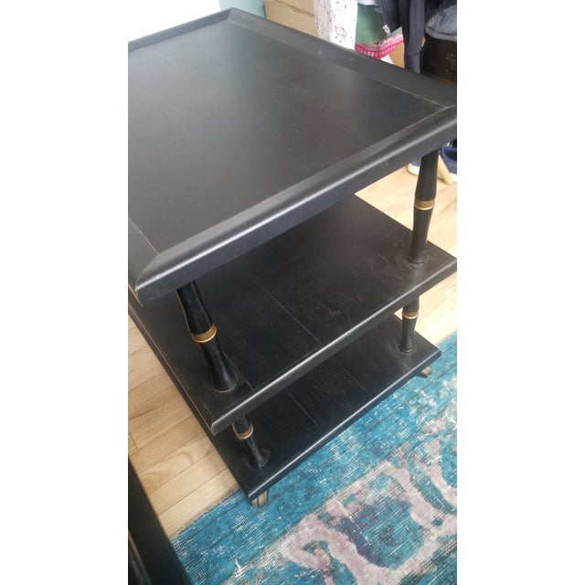 A pair of Hollywood Regency three tier black side tables with gilt detail on bamboo motif supports and claw feet.