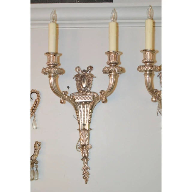 Silver over bronze pair of sconces, circa 1900. Measures: 22" height x 11" width x 5.5" deep.