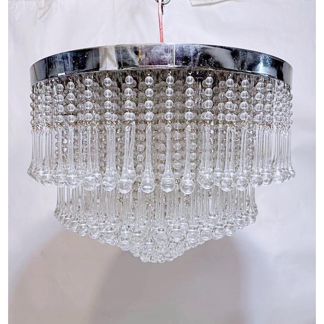 Mid-Century chandelier with chrome rim and hand blown crystal teardrops. It has 8 candelabra based sockets that can use...