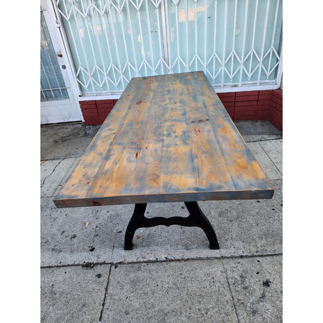 Rustic dining table has a thick solid wood top with a distressed blue and brown finish. The base consists of two heavy-...