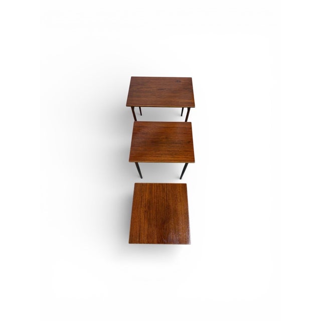 This stylish set of three Mid-Century Modern walnut nesting tables offers timeless design and everyday versatility....