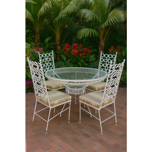 Gorgeous vintage wrought iron patio dining set by Arthur Umanoff featuring a round glass-top table and four matching high-...