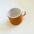 A mid century ceramic creamer pitcher from the "Mediterrania" line by Mikasa. Orange exterior with a white interior and...
