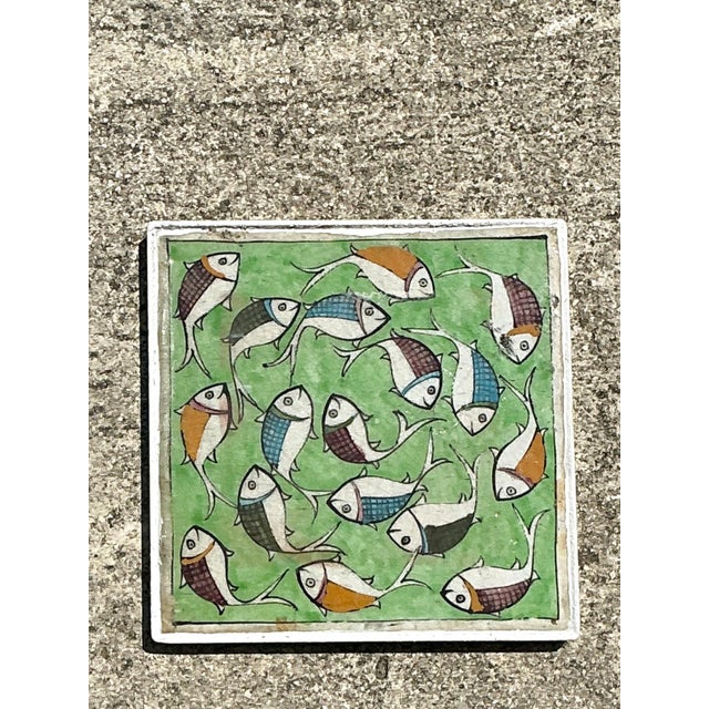 This vibrant vintage ceramic tile is a captivating example of mid-century decorative art, featuring a whimsical school of...
