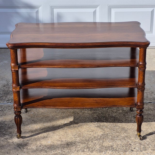 This is an elegant regency style 4-tiered occasional table on wheels by luxury American furniture maker Henredon. The...
