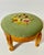 Vintage round wooden footstool with a sage green floral needlepoint top and short curved legs. The floral needlepoint is a...