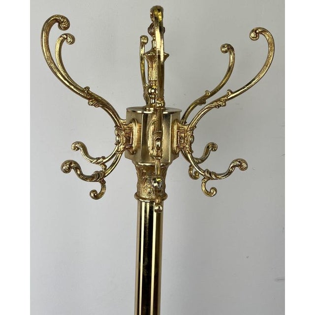 An elegant Vintage French brass standing coat hanger with an ornate traditional design, multiple curved hanging hooks and...