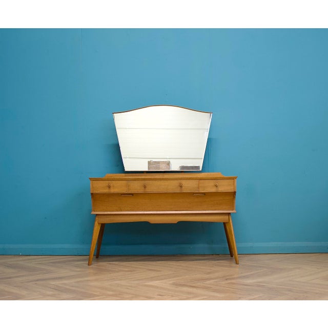 A stylish mid-century dressing table by Alfred Cox, dating from the 1950s. Crafted in figured walnut veneers, it features...