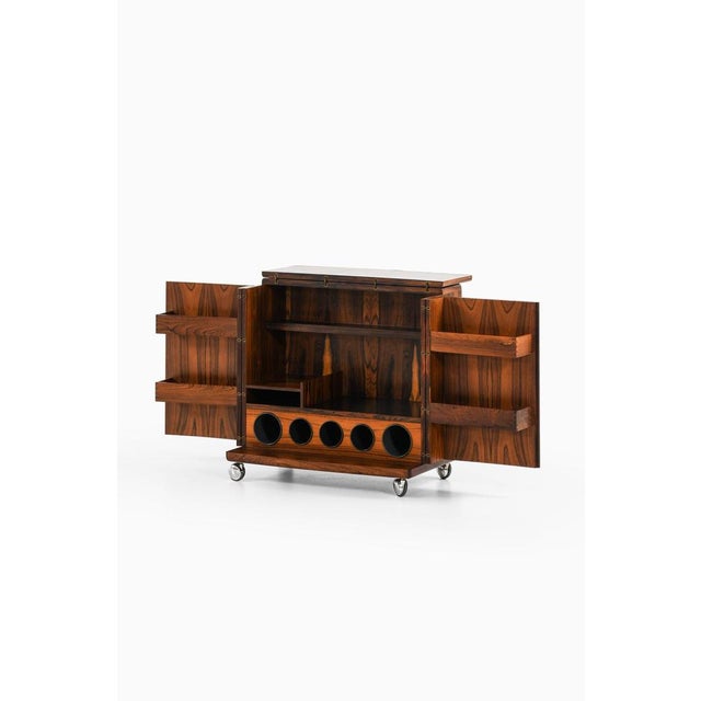 Bar cabinet on wheels in rosewood, brass, formica and steel by illum wikkelsø, 1960's material: rosewood, brass, formica...