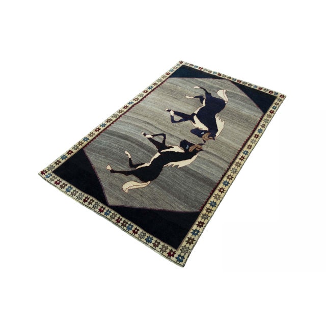 An extraordinary hand-knotted Gabbeh nomad rug with an impressive horse motif. The harmonious gray tones combined with the...