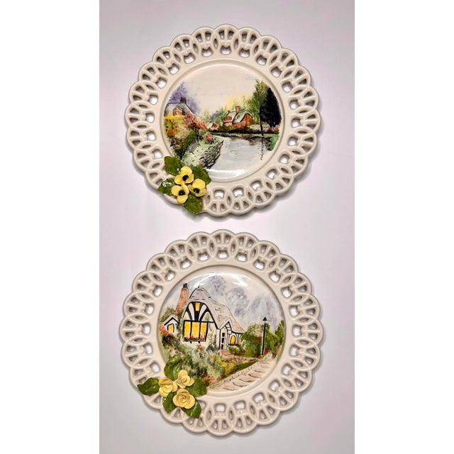 Each filigree bordered ceramic plate in this set of four depict a hand painted scene of various settings of English or...