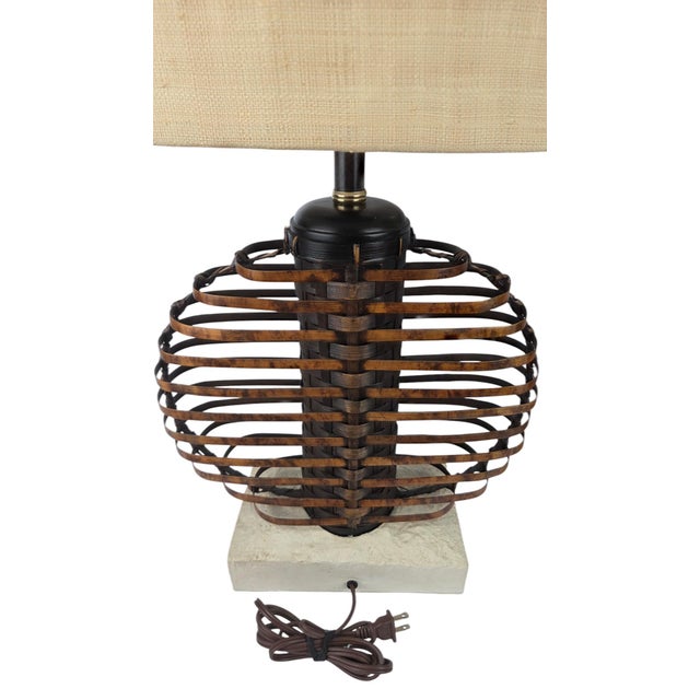 A striking pair of Palecek table lamps featuring sculptural open-cage bodies of flat woven rattan and bamboo in a ribbed...