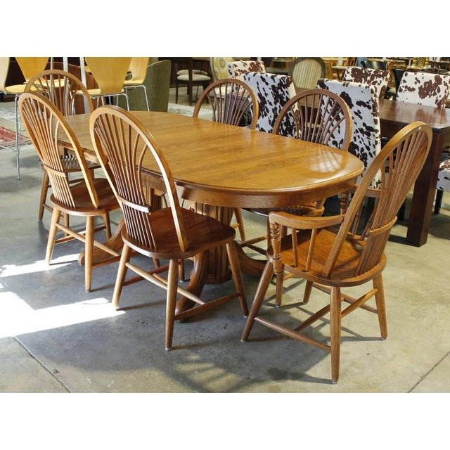 This set features a traditional oval dining table crafted from solid oak, supported by a sturdy double‑pedestal base with...