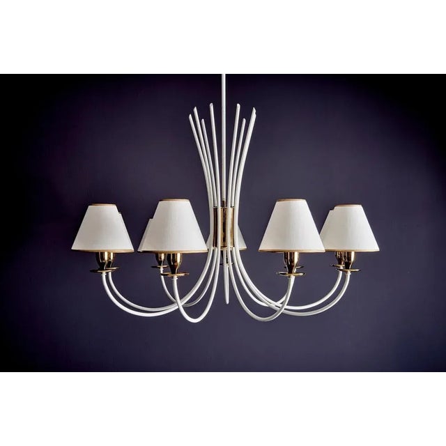Elegant nine-arm chandelier in the manner of Jean Royère. It features gracefully curved white lacquered arms extending...