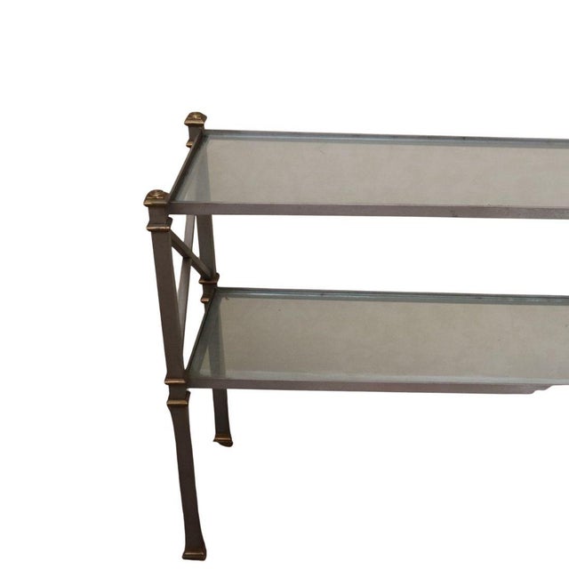 A two tier sleek metal and glass console table attributed to Maison Jansen, designed in the refined style of the...