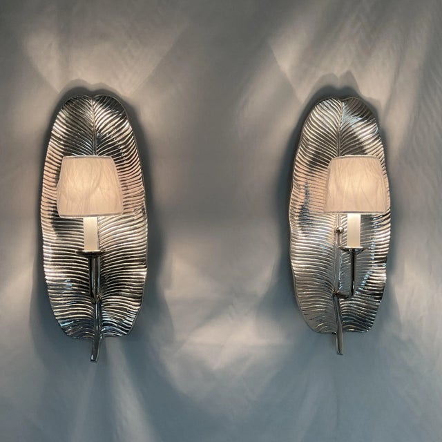 Elevate your interior decor with this stunning set of two silver wall sconces, each crafted with a sleek, leaf-inspired...
