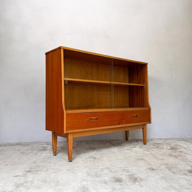 This mid century teak bookcase and display cabinet by Jentique combines glazed display space with two useful drawers...