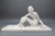 A sculptural mid-century ceramic figure depicting a seated female nude, executed in ceramic with a white painted or slip-...