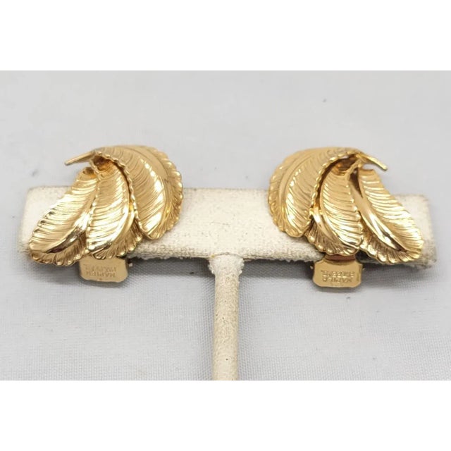This is part of Chairish’s Costume Jewelry assortment. 1960s goldtone cluster of 3 feathers clip back earrings. Marked...