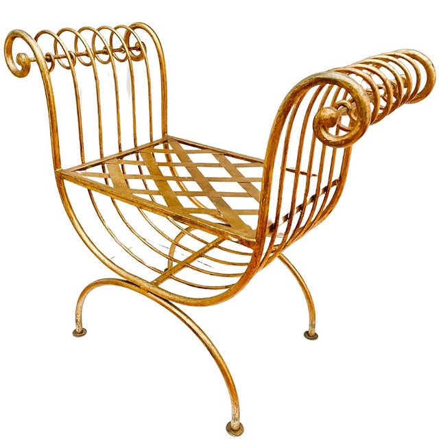 Mid-century 1960s Italian gold gilt wrought iron curule bench in a glamorous Hollywood Regency style. It has been...