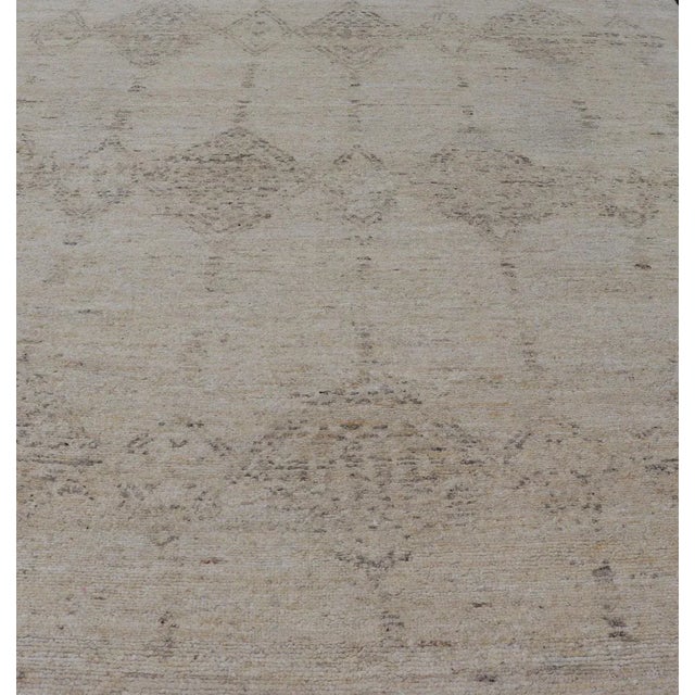 Measures 11'10 x 14'8 This Indian modern rug features an all beige and cream blended field with Moroccan styled tribal...