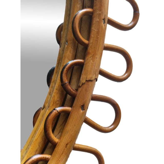 The mirror consists of an oval glass surrounded by an ingenious frame formed by two turns of bamboo joined by a dense...