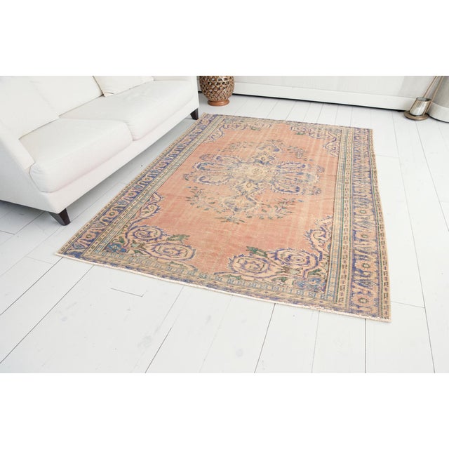 This is a vintage Turkish Oushak rug from the Mid 20th Century. The piece was hand-knotted.