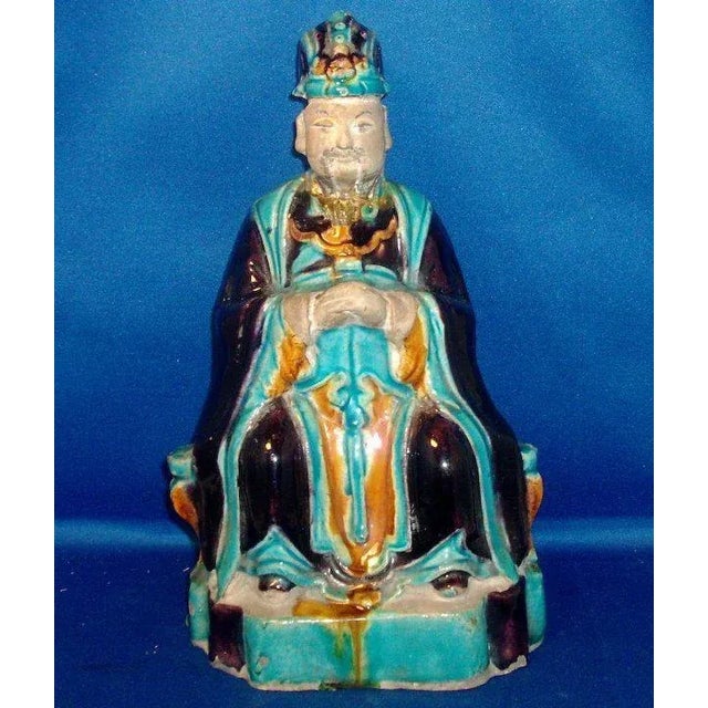 Antique Chinese seated ceramic figure of an official in traditional robes, Ming Dynasty. Decorated in shades of aubergine,...