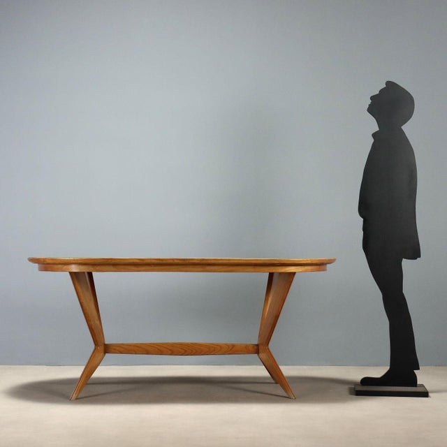 1960s vintage table featuring an elegant and functional design. The elliptical top is crafted from wood and treated glass,...