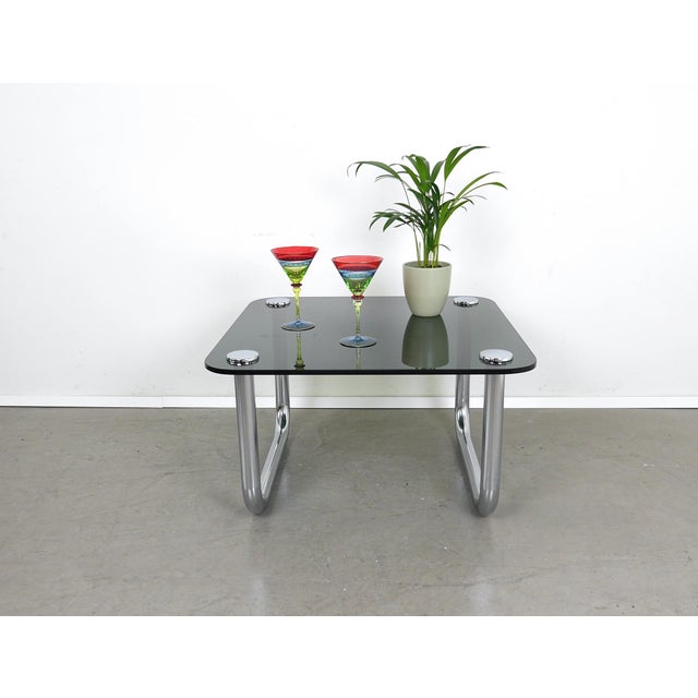 Square Space Age coffee table from the 1970s. The smoked glass top is rounded at the corners and is supported by two...