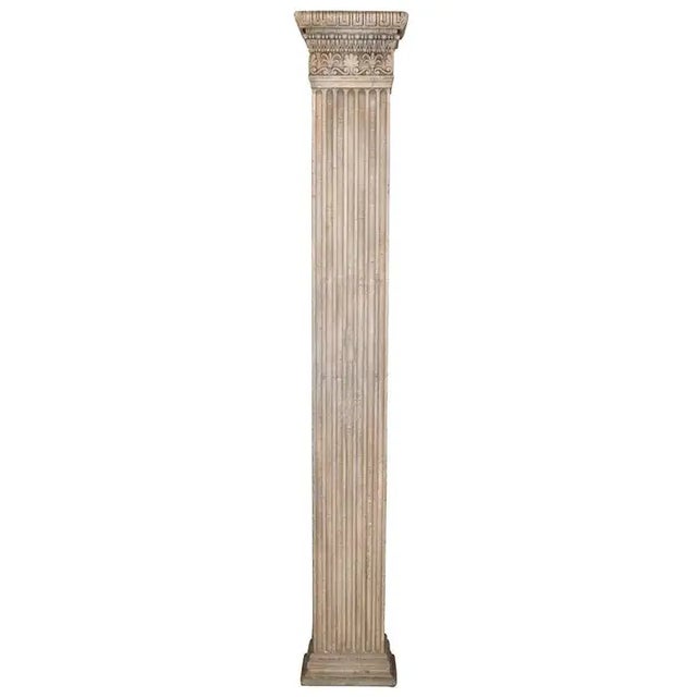 Elegant pair of tall wooden columns, painted in a light neutral tone, featuring crown molding details at the top and...
