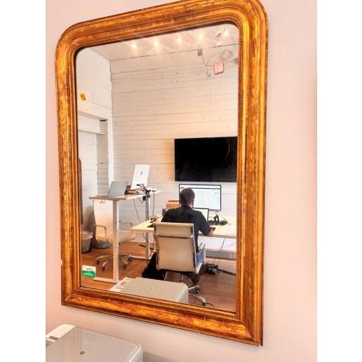 Large French giltwood Louis Philippe mirror featuring a classic rectangular form with softly rounded upper corners,...