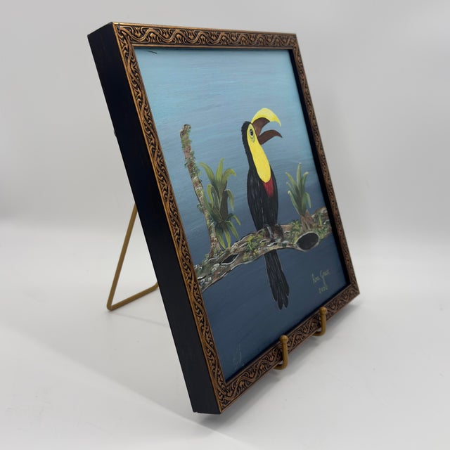 Original tropical bird painting featuring a toucan perched on a branch surrounded by green foliage against a soft blue...