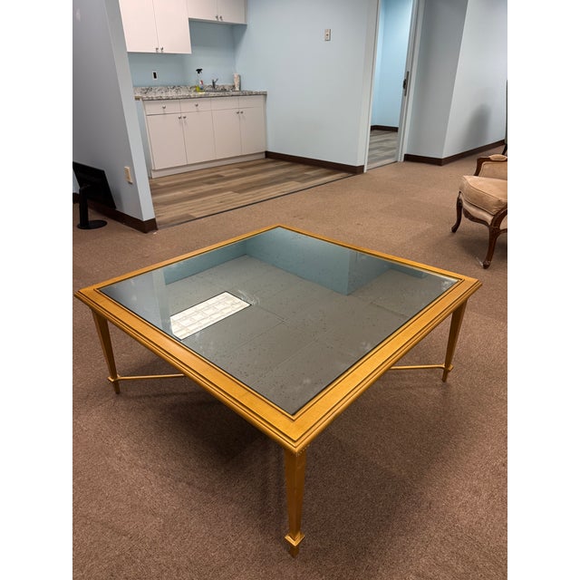 Elegant gilt coffee table featuring a mirrored glass top and clean Neoclassical lines. Hollywood Regency–inspired design...