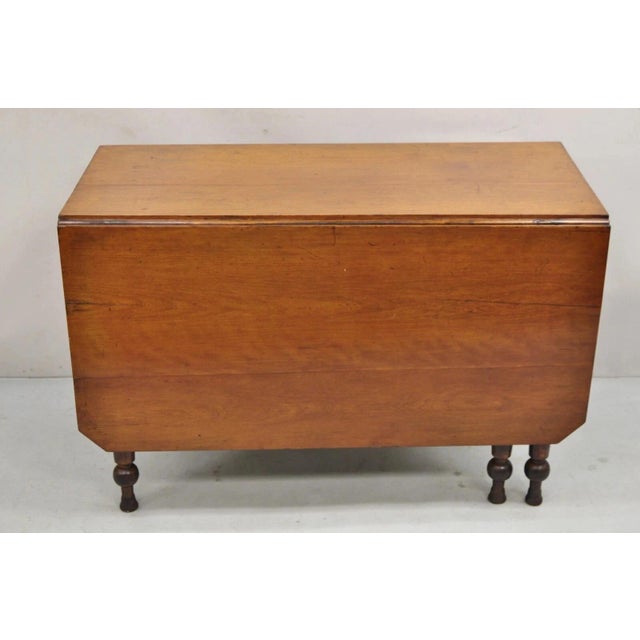 Antique American Colonial Cherry Wood Gateleg Drop Leaf Farmhouse Dining Table. Item features carved bulbous legs,...