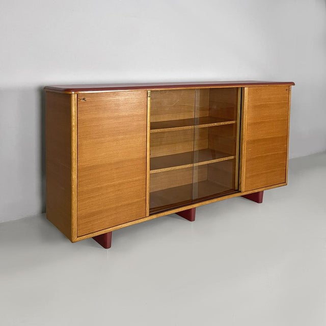 Italian mid-century modern sideboard in wood, glass and burgundy leather, 1960s Sideboard or display with a contoured top...