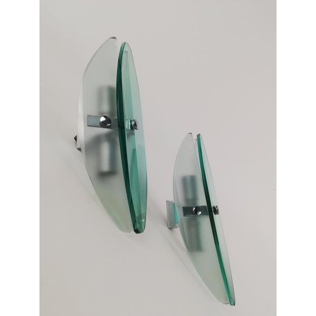 A pair of vintage sconces datable between the 1960s and 1970s of the 20th century. These Italian wall lights are...