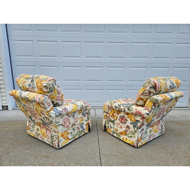 A pair of Baker Furniture swivel club or armchairs with what is believed to be chintz fabric with a floral print over a...