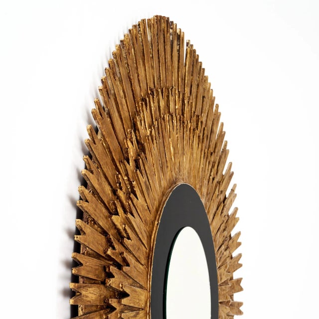 Large sunburst mirror from Spain made of hand-applied gold-leafed wood. The rays emanate from a circular central mirror...