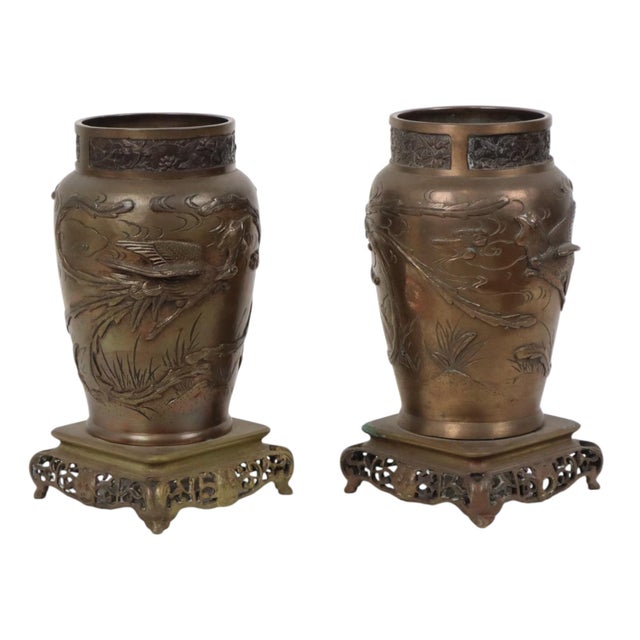 A pair of Japanese bronze vases with high relief decoration of phoenixes and flowers; the neck is also extensively...
