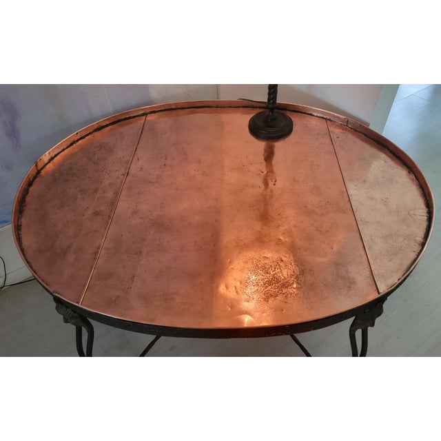 19th century French elliptical table with copper insert top. Four shaped metal legs terminating in metal masks. Shaped...