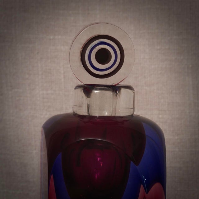 A perfume bottle with internal decorations in various shades of blue, pink, and transparent. A sculpture of the highest...