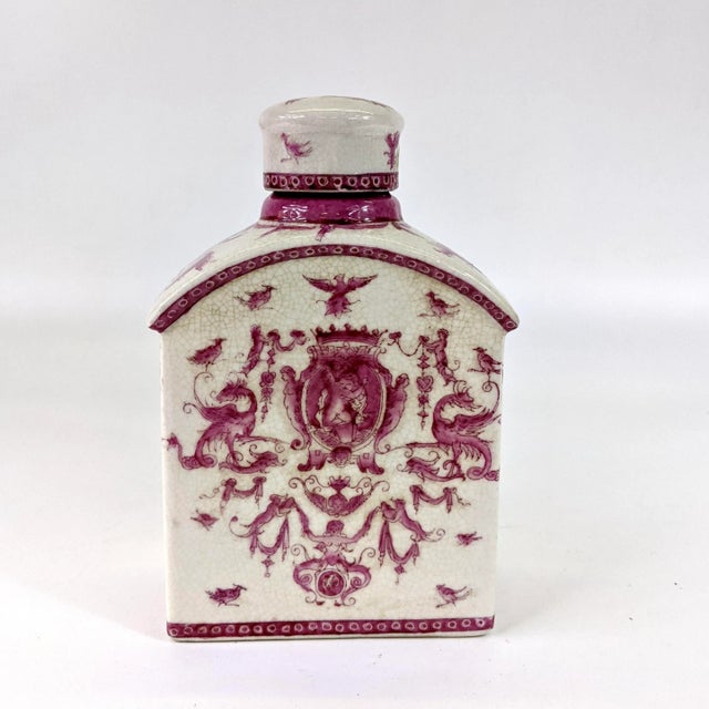 A small porcelain bottle that is intricately hand painted with designs of mystical creatures. Lid has minor repairs