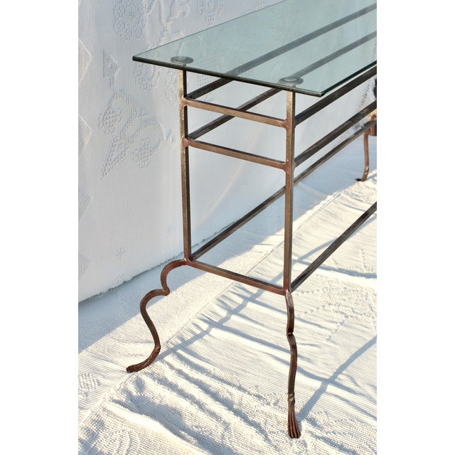 Handmade forged wrought iron sofa table with a glass type. Hammered and detailed feet in dark metal. Curved detailing on...
