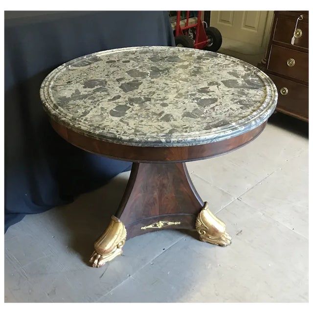 Fine C. 1830 French Charles X period mahogany center table with original mottled gray grooved marble top. Has a tripartite...