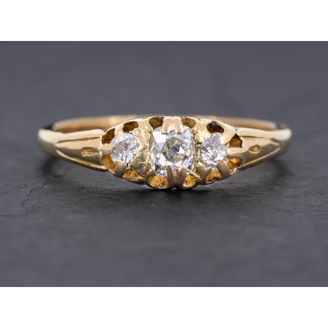 Edwardian diamond three stone ring featuring one cushion shape old mine cut diamond accented by one round old mine cut...