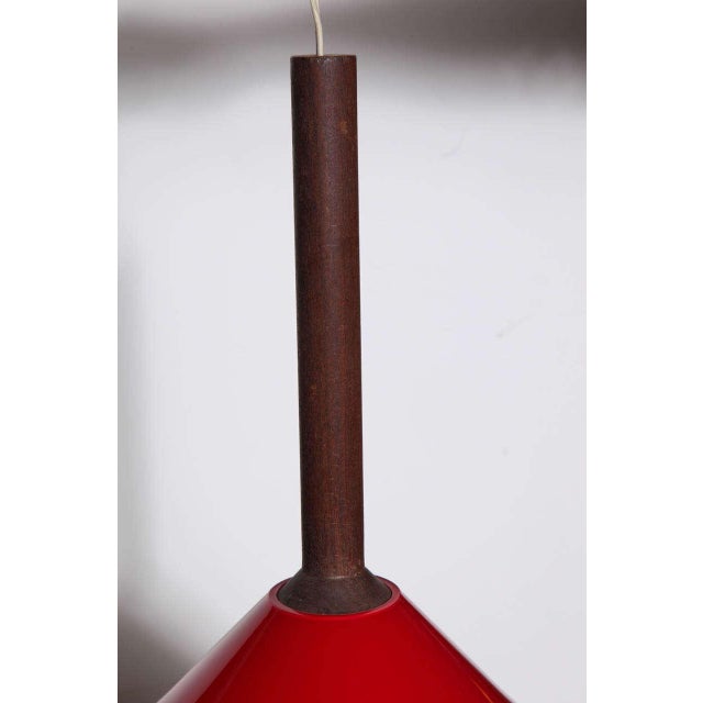 Scandinavian Modern Tapio Wirkkala Teak hanging pendant with red cased glass Vistosi shade. Featuring a suspended 12.5H...